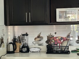 A kitchen with a blender, kettle, and coffee maker on the counter.