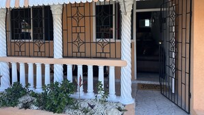 A building with a covered porch, columns, and a gated entrance. - Remarkable 1-bed Apartment in Montego Bay (Montego Bay)
