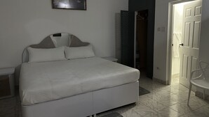 A neatly arranged bedroom with a bed, a wardrobe, and a door leading to another room. - Remarkable 1-bed Apartment in Montego Bay (Montego Bay)