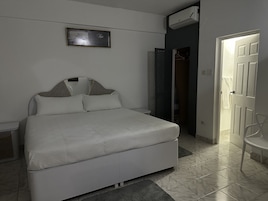 A neatly arranged bedroom with a bed, a wardrobe, and a door leading to another room.