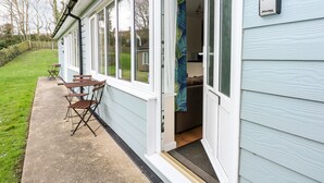 Una casa con un cartel con el número 10, una puerta abierta a un cuarto y un pequeño espacio exterior con una mesa y sillas.