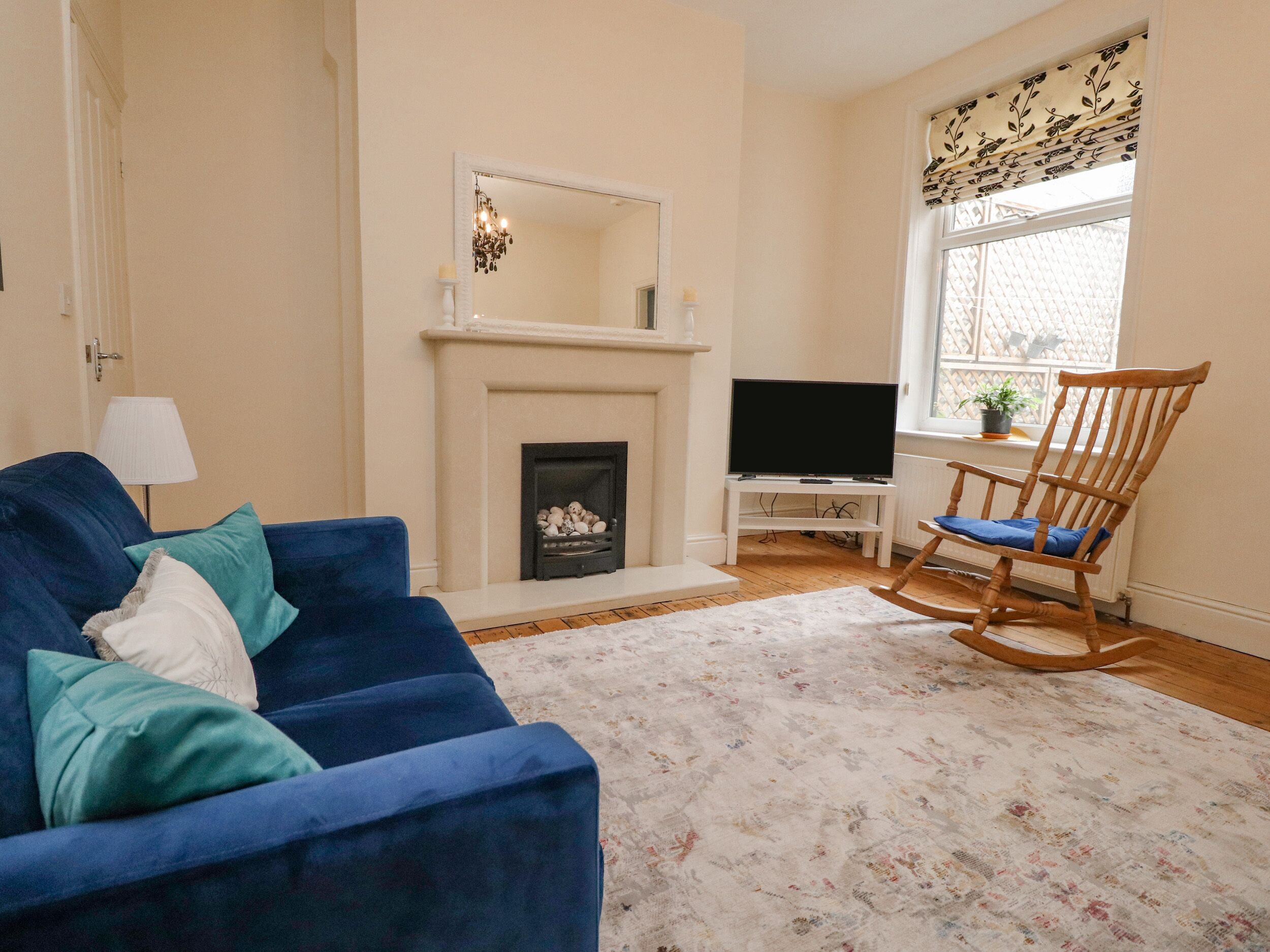 A living room with a blue sofa, a fireplace, a television, and a rocking chair.