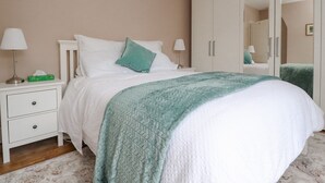 Un dormitorio ordenado con cama, mesitas de noche, un armario y un espejo.