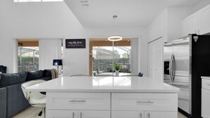 A modern kitchen with a central island, white cabinetry, and a stainless steel refrigerator.