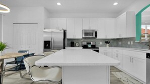 A modern kitchen with white cabinets, stainless steel appliances, and a central island.