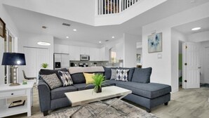 A modern living room with a grey sectional sofa, a white coffee table, and a staircase leading to an upper level.