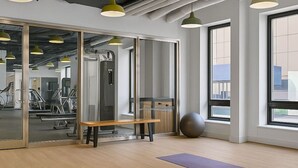 Un gimnasio moderno con equipo de ejercicio, ventanas amplias y un banco de madera.