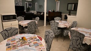 Zona de dinar amb taules rodones cobertes amb diaris, envoltada per caires amb estampats.