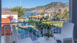 A balcony with white wicker furniture, a pool, and a view of the sea and mountains. - Lavinya Selimiye Buotique Hotel (Marmaris)