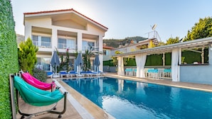 A pool area with a hammock, lounge chairs, and a building with balconies. - Lavinya Selimiye Buotique Hotel (Marmaris)