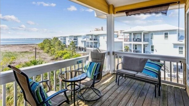 Eine Holterrasse mit Sitzgelegenheiten im Freien, mit Blick auf einen Strand und Wohnhäuser.