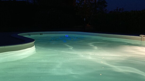A swimming pool at night with a clear water surface and a visible edge.