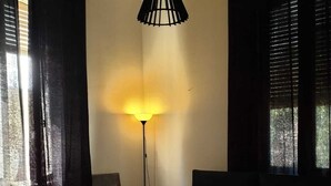 Une chambre à coucher avec un lit, une chaise, une lampe sur pied et des rideaux.