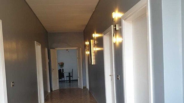 Un couloir doté d’un sol à motifs, de portes blanches et de luminaires fixés au mur.