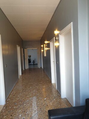 A hallway with a speckled floor, white doors, and wall-mounted light fixtures. - 800 meters from the sea (Rimini)