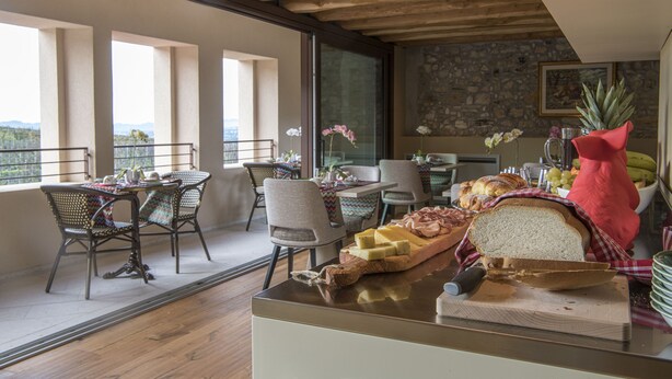 Un espace repas doté d’un plafond en bois, d’un mur en pierre et de grandes fen êtres offrant une vue panoramique.