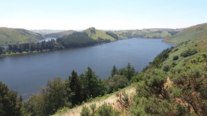 Un lago rodeado de colinas con densos bosques y un cielo despejado.