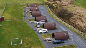 Un estacionamiento con varias cabañas de madera, un campo de fútbol y una zona cercada.