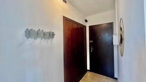 A hallway with a wooden door, a dark door, and a wall-mounted light fixture. - Bright apartment for a pleasant stay in Hyères (Hyères)