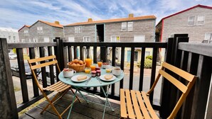 Un balcon avec une table préparée pour le petit-déjeuner, comprenant des toasts, des fruits et des boissons.