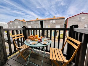 A balcony with a table set for breakfast, including toast, fruit, and beverages.
