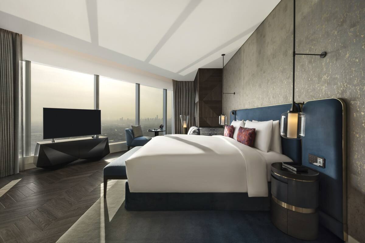 Een moderne hotelkamer met een groot bed, een flatscreen televisie, een nachtkastje en uitzicht op de stad.