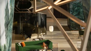 A modern interior with a green sofa set, a marble coffee table, and a unique geometric light fixture.