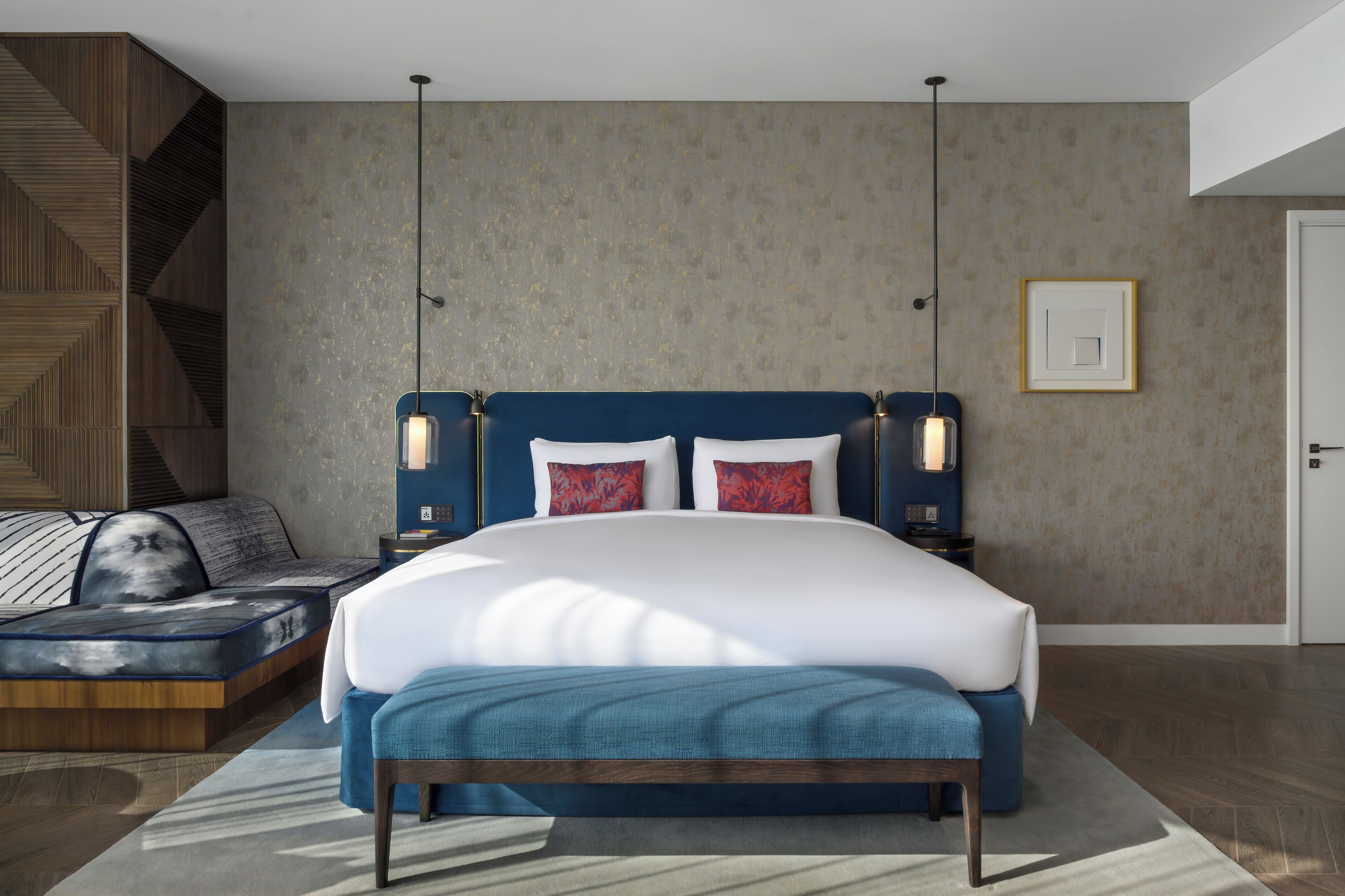 A modern bedroom with a large bed, a sofa, and a nightstand.