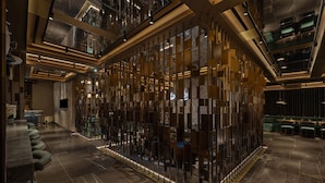 A modern hotel lobby with a central seating area, a reception desk, and a high ceiling with skylights.