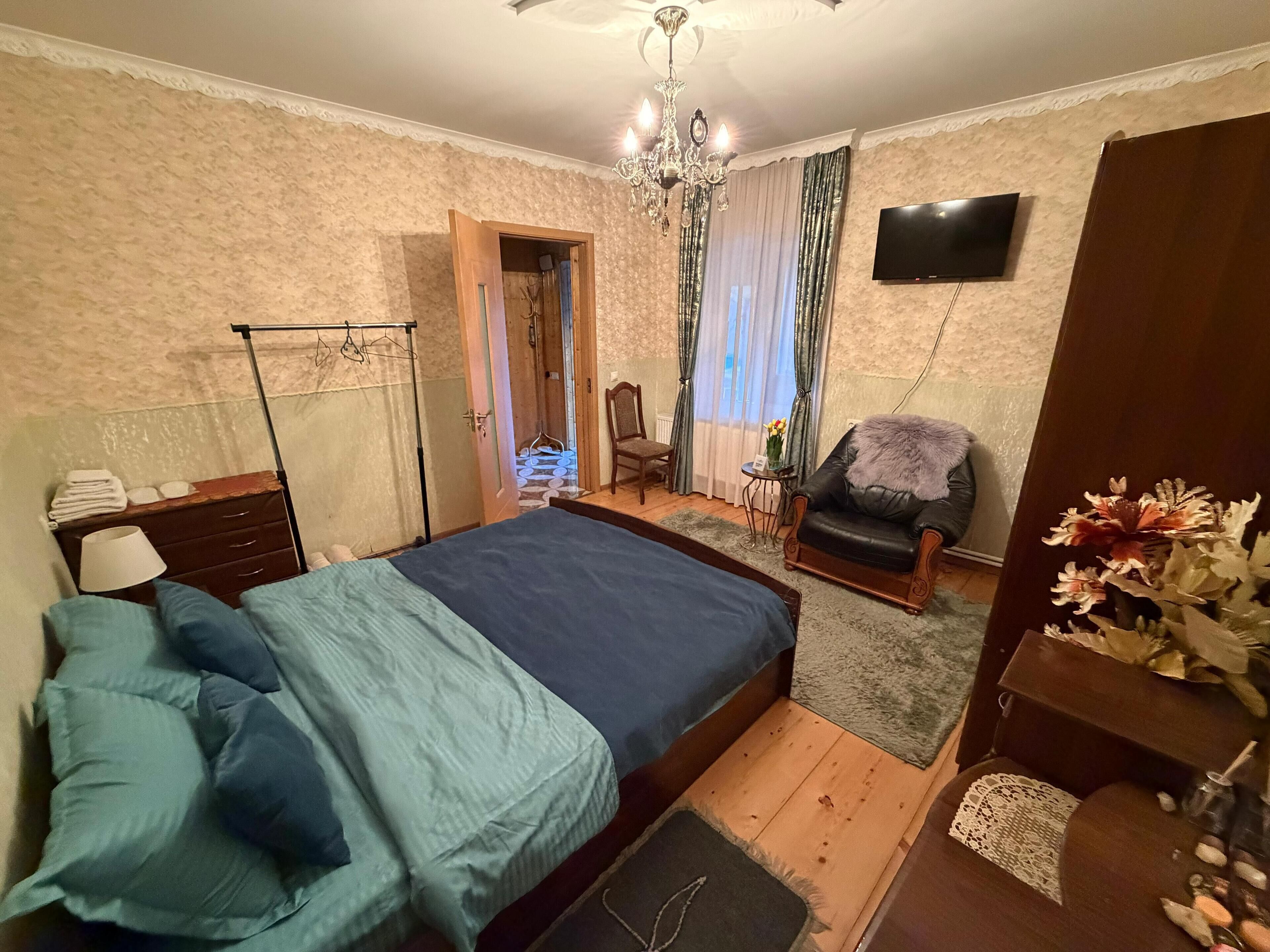 Ein Schlafzimmer mit einem Bett, einem Sessel, einem Fernseher und einer Chandelüster.