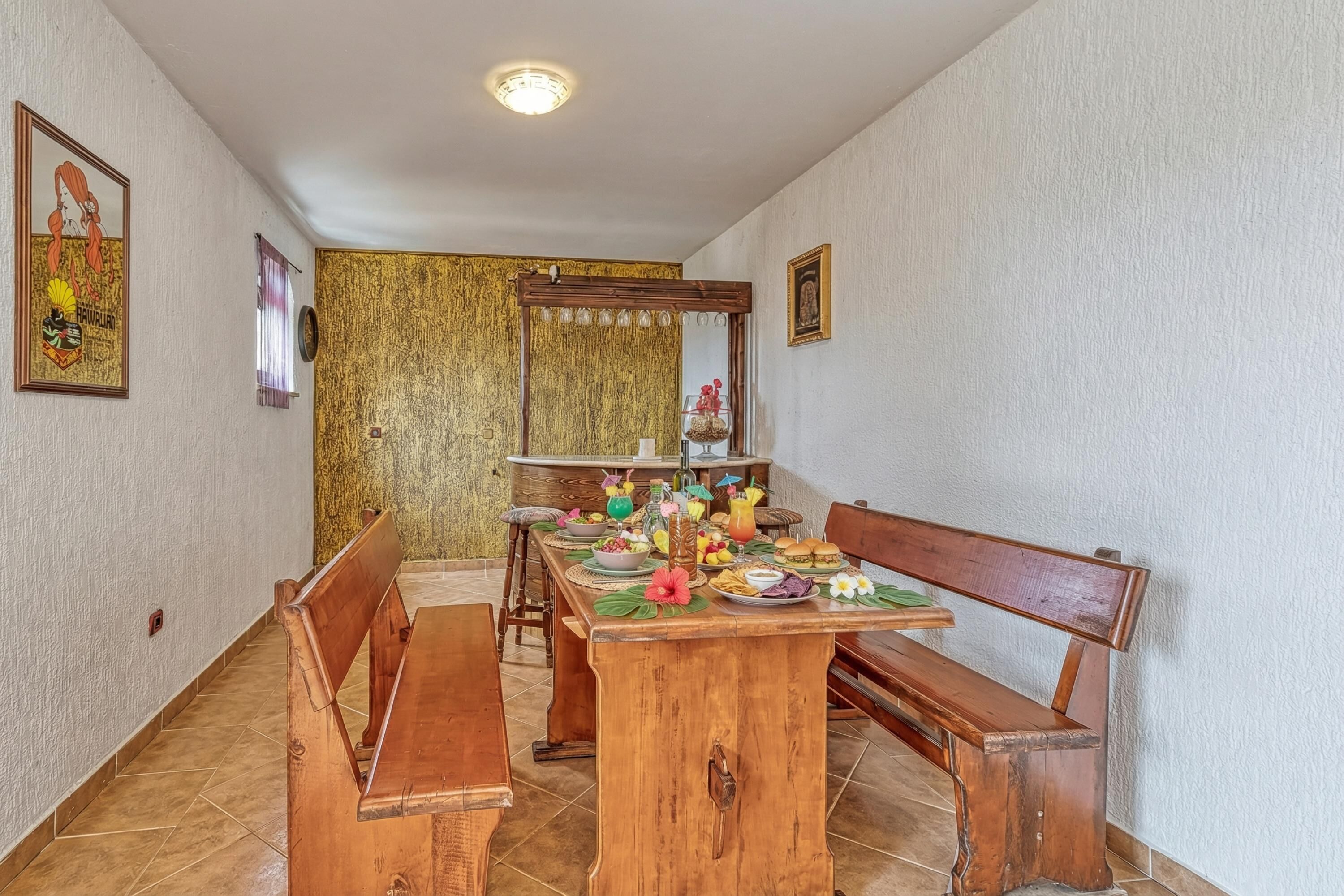 A dining area with a wooden table, benches, and a variety of food and drinks.