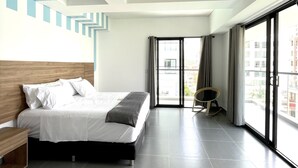 Habitación de hotel moderna con una cama grande, cabecera de madera, balcón con vistas y un diseño geométrico en la pared.