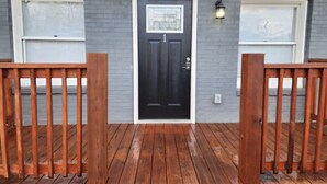 A house with a black front door, two garage doors, and a wooden deck.