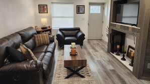 A living room with a leather sofa, a wooden coffee table, and a fireplace.