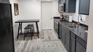 A compact kitchen with a refrigerator, a microwave, a sink, and a dining area with a table and chairs.