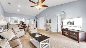 A spacious living room with a ceiling fan, a TV displaying 'Branson Lakes Lodging', and a cozy seating area with a coffee table. - Gorgeous, Pools, Hot Tub, Golf, 3 Min To Strip! (Branson)