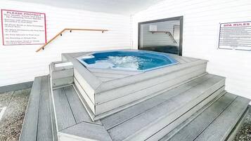 A hot tub with steps leading up to it, surrounded by white walls.