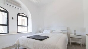 Un dormitorio con cama, mesita de noche y ventana.