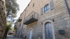 Un edificio de piedra estrecho con un balcón, una puerta grande y una ventana pequeña.