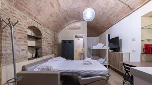 Una camera compatta con un letto, una scrivania e una televisione.