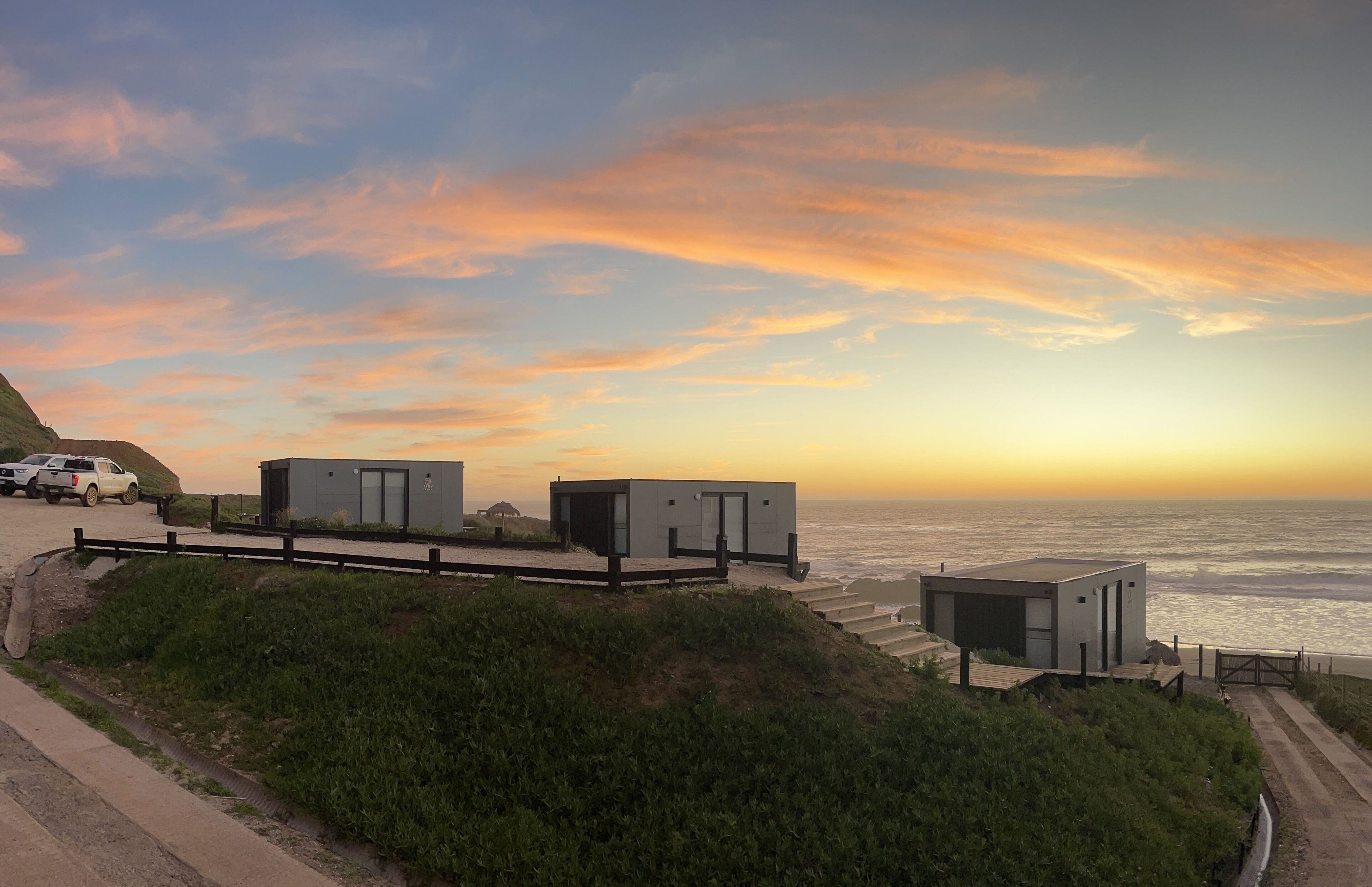A coastal view with modern buildings, a road, and a grassy area.