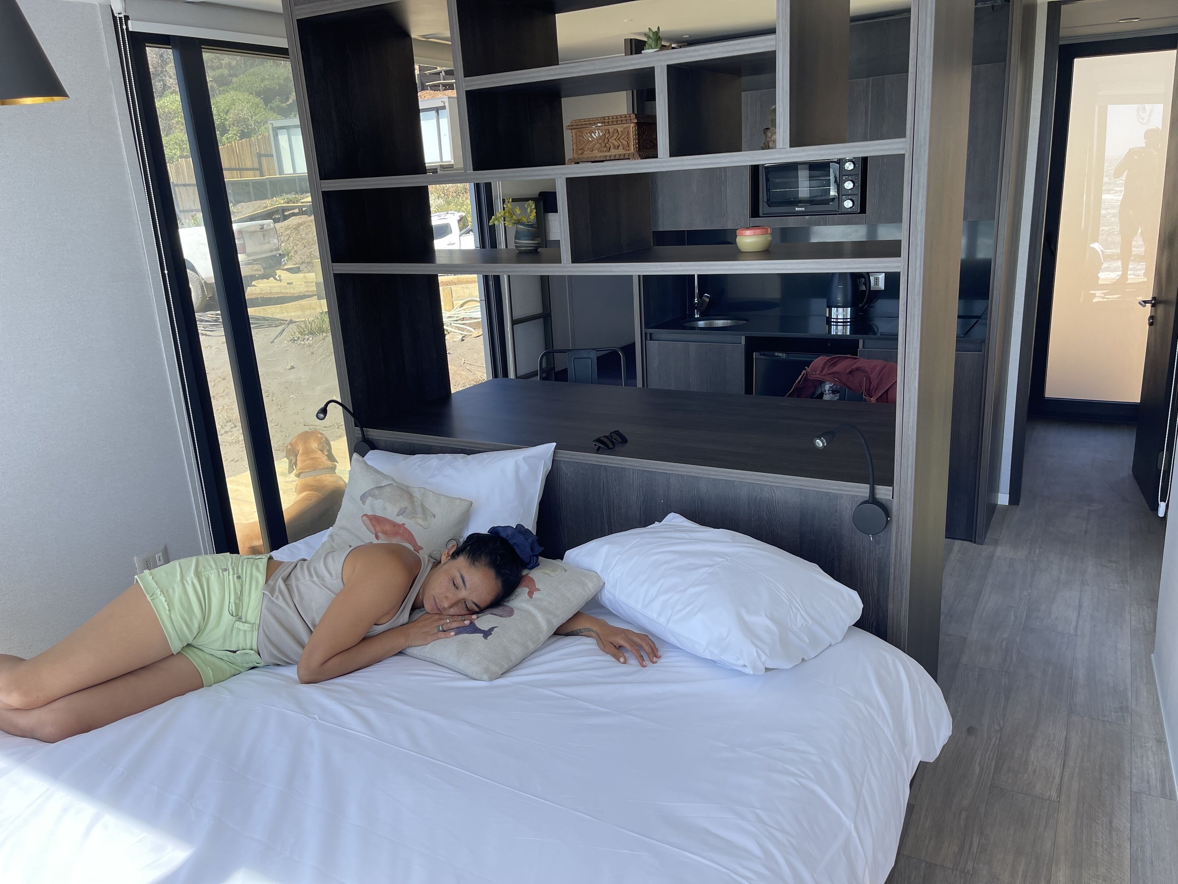 Un dormitorio moderno con cama, escritorio integrado y kitchenette.