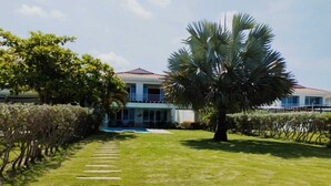 Ein modernes Haus mit gepflegtem Rasen, einem Kiesweg, der zum Eingang führt, und einer großen Palme.