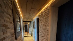A hallway with exposed brick walls, wooden flooring, and recessed lighting. - Arnold LUXE & COSY Chalet for 14 People in Les Masses (Les Masses)