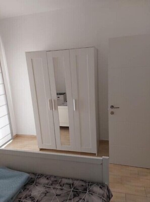 Features a spacious wardrobe with multiple doors and a mirror, along with a standard door and a window.