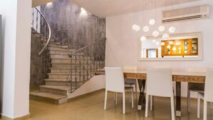 Ein moderner Essbereich mit Treppe, weißen Stühlen und Pendelleuchten.