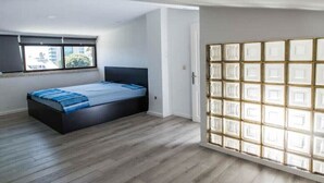 Ein Schlafzimmer mit einem Bett, einem Fenster und einer Schiebetür mit geometrischem Muster.