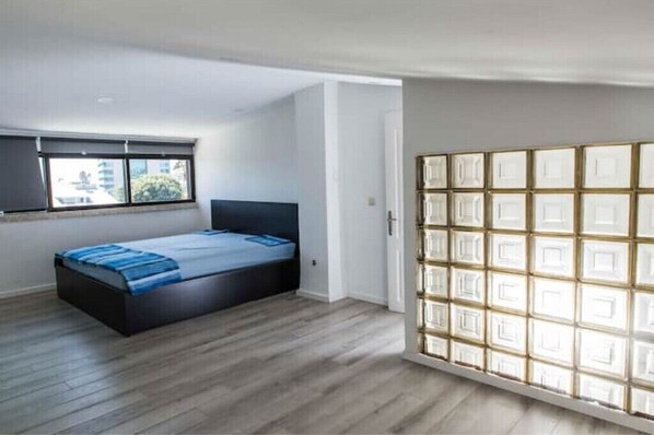 A bedroom with a bed, a window, and a sliding door with a geometric pattern.