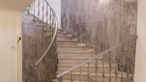 Eine moderne Treppe im Spiralstil, mit Metallgeländern und einer Betonwand.