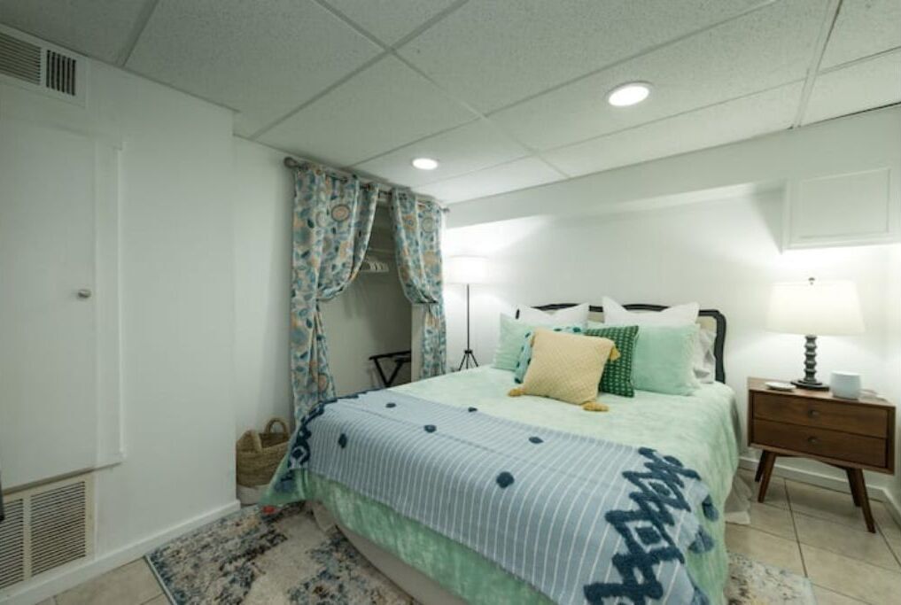 Une chambre à coucher avec un lit, une table de chevet, une lampe et des rideaux.